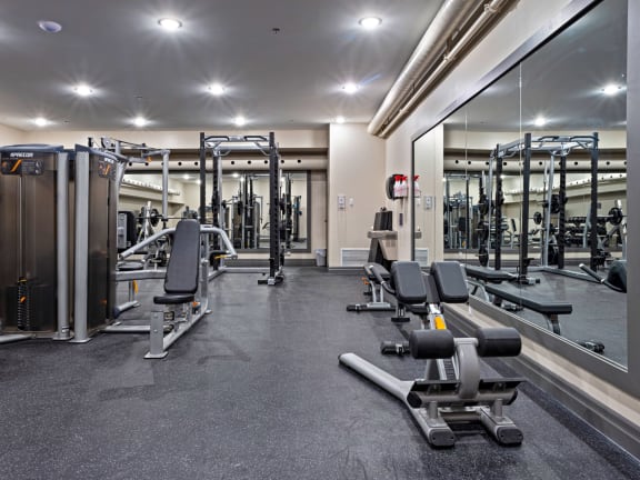 a gym with weights and cardio equipment and a large glass wall