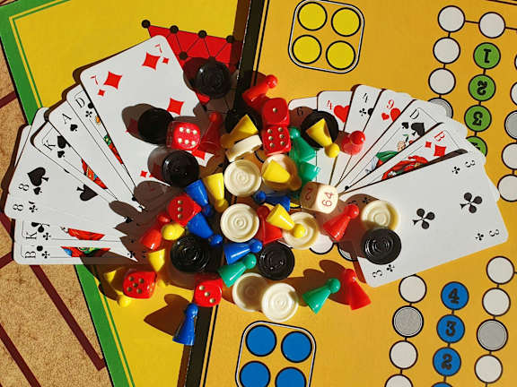 A pile of playing cards and dice are scattered on a table.