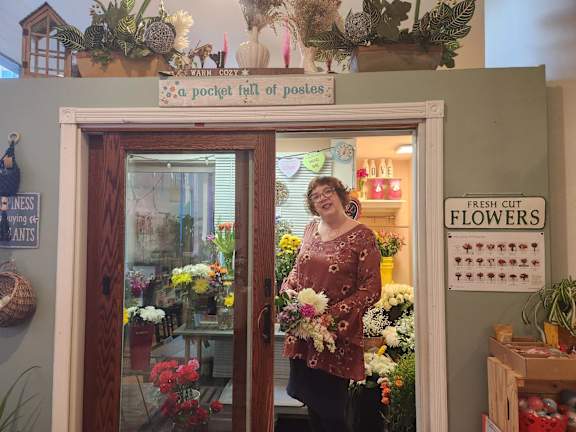 a woman standing in a flower shop holding a bouquet of flowers