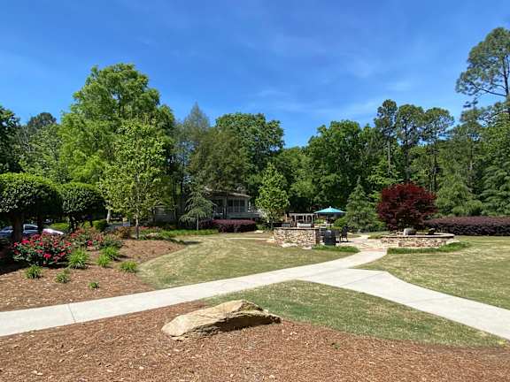 A park with a large rock in the middle of a dirt area.