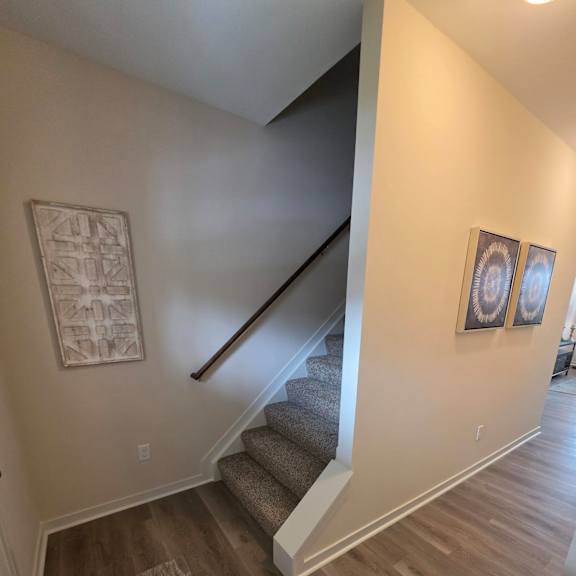 A staircase with a wooden handrail and a carpeted runner.