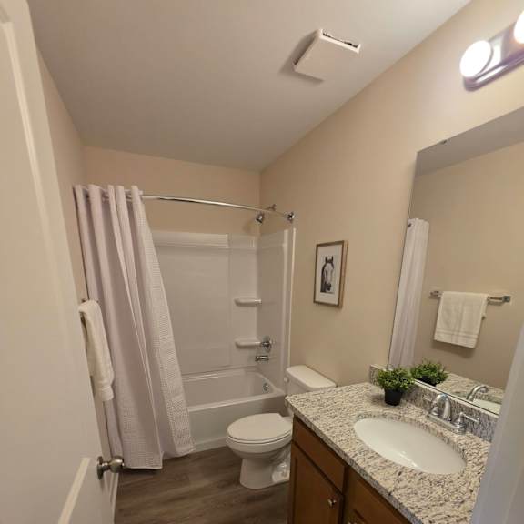 A bathroom with a toilet, sink, and a mirror.