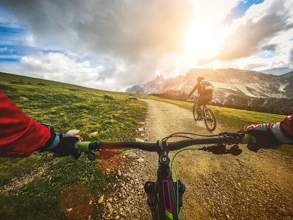 A person riding a bicycle on a dirt road in the mountains.