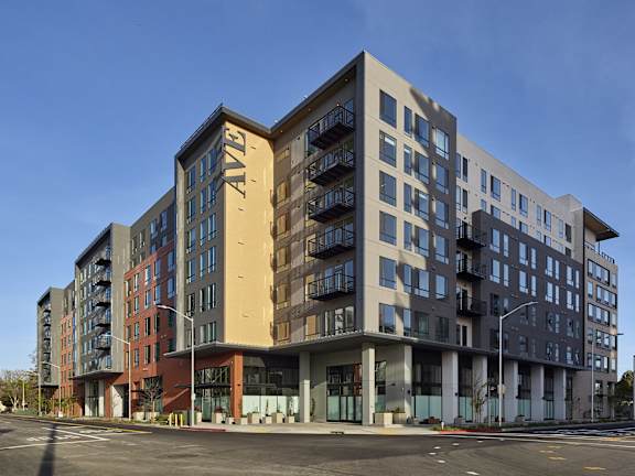 A large, modern apartment building with multiple balconies and a variety of window designs.