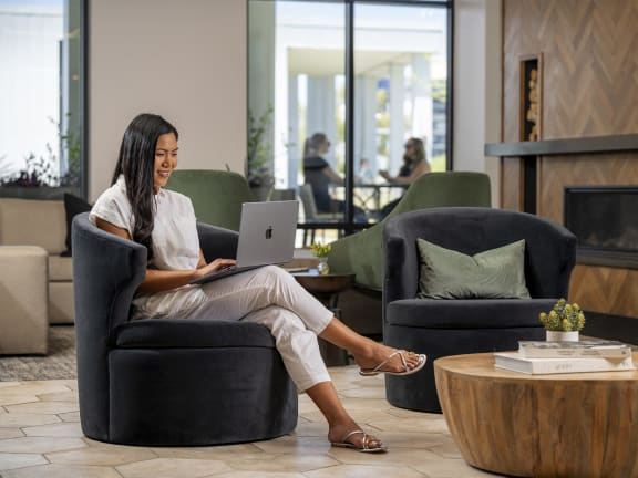A woman is sitting in a chair with a laptop on her lap.at AVE Santa Clara, Santa Clara