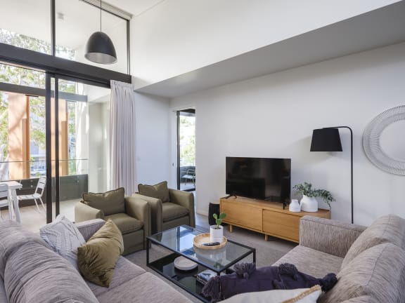 a living room with a couch and a glass coffee table and a tv