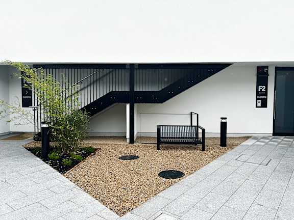 a metal bench in front of a white building with a staircase
