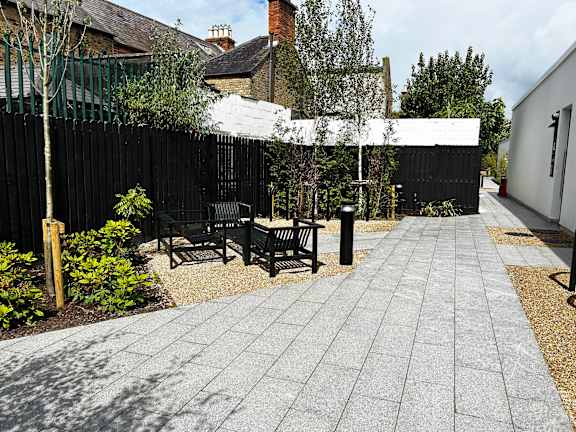 a small courtyard with benches and a table in front of a fence