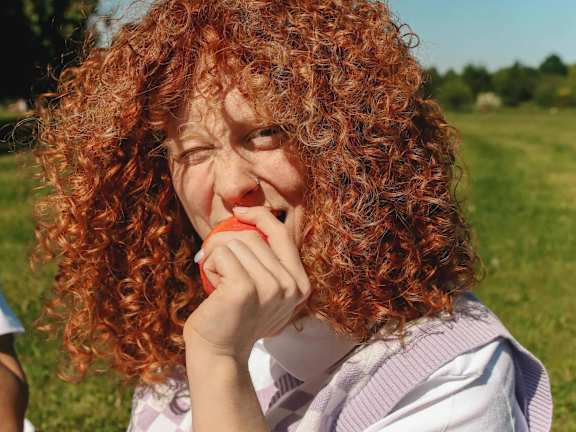 A person with curly hair eating an apple.at Chalkwood Apartments, Ebbsfleet Valley