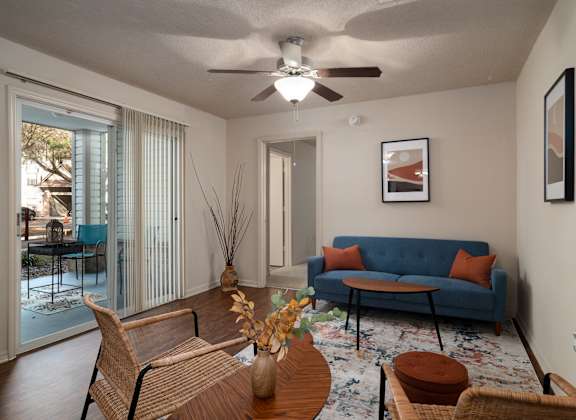 A living room with a blue couch and a wooden table at Tivoli Apartments, Gainesville, 32608
