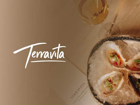 A glass of wine and a plate of oysters with the word  at Aria, New York, 10038