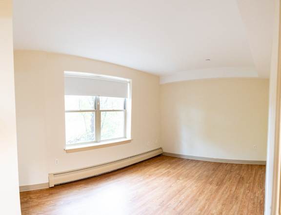 an empty room with a window and wood floors