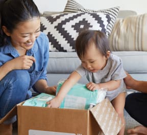 a woman and a man are sitting on the floor with a baby in a box