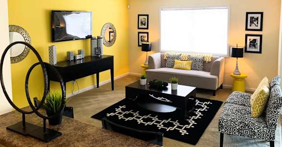 A living room with a yellow wall and a television. at Sienna Ridge, Atlanta, GA