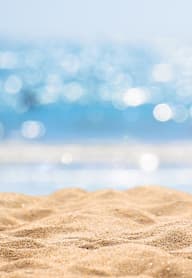 A close up of a sandy beach with a blurred blue background.