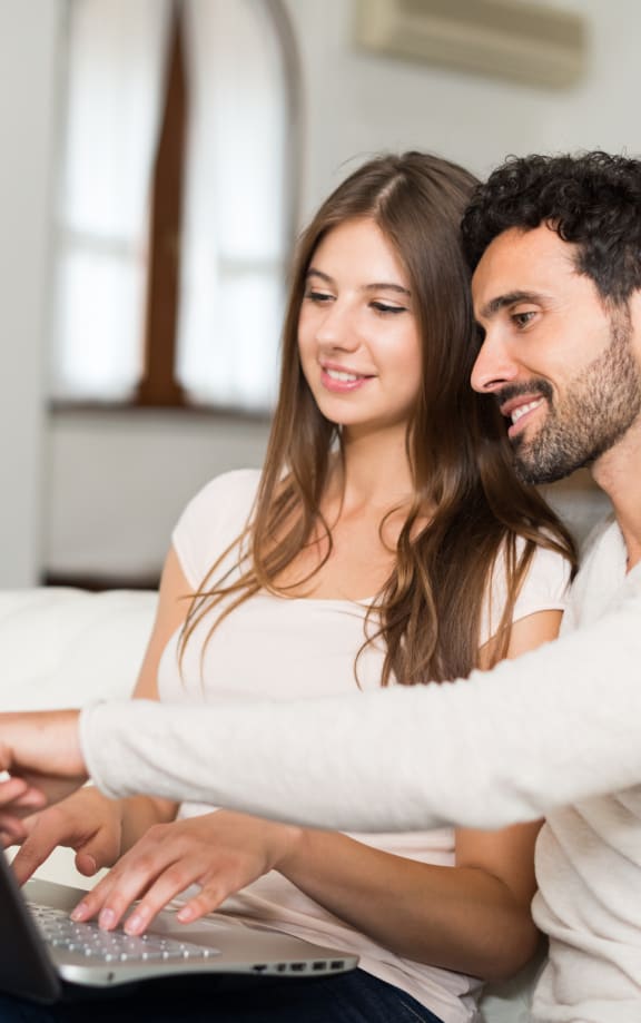 couple sitting on a couch using a laptop computer