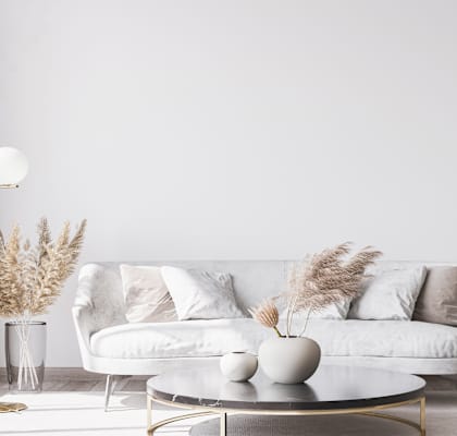 A white couch with a grey vase on a coffee table in a room.