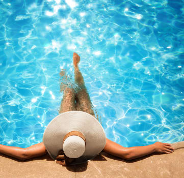 a woman laying in a pool with her hat on