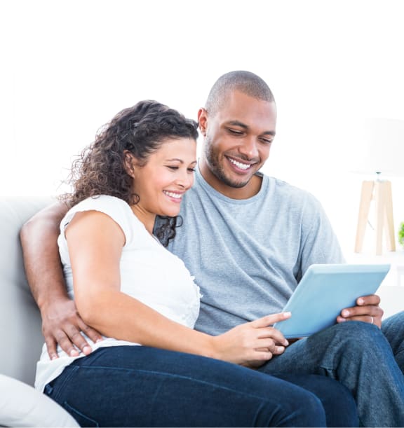 a couple sitting on a couch looking at a tablet