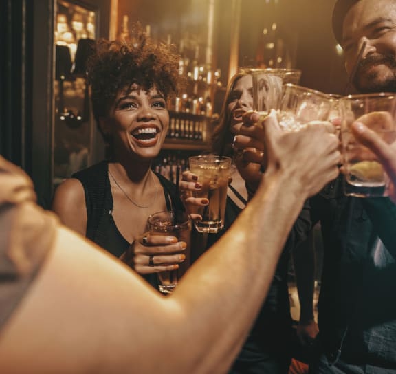 a group of people celebrating with drinks at a bar