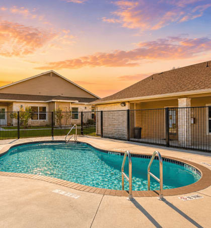 A sunset view of a pool and a house.