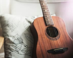 Acoustic Guitar Laying on Throw Pillow on Chair