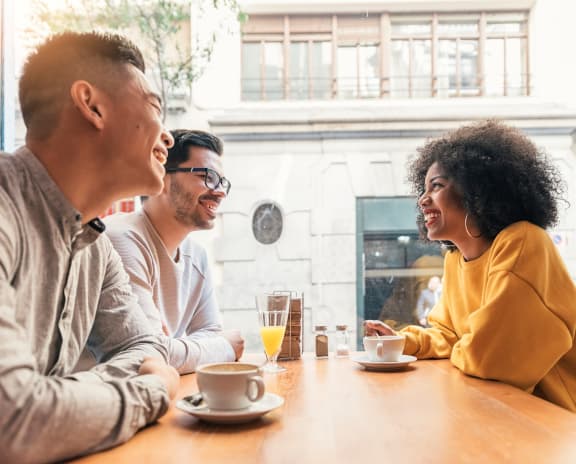 Group of 3 Sitting at Cafe Table with Coffee and Beverages on Table