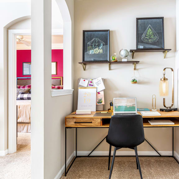 a home office with a wooden desk and a black chair