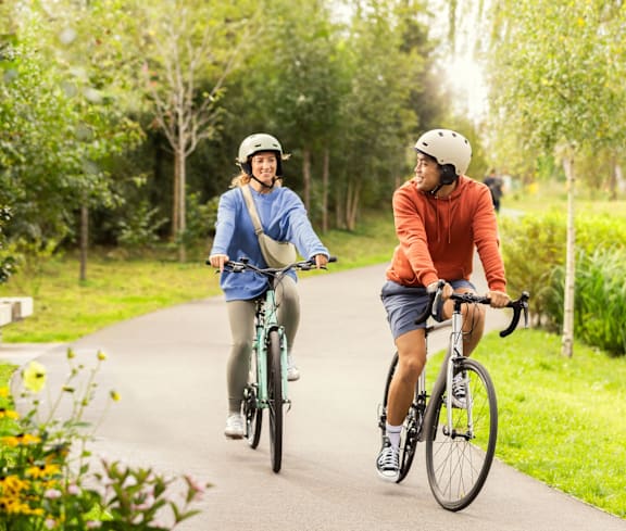 Two people riding bikes on a path in a park.