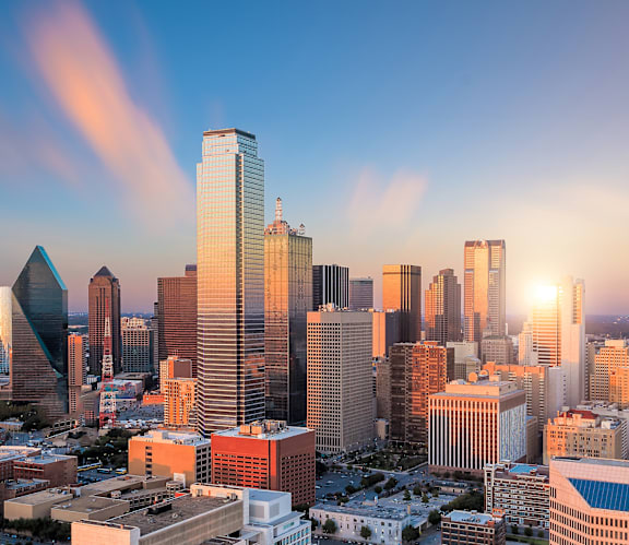 A city skyline with tall buildings and a sunset in the background.