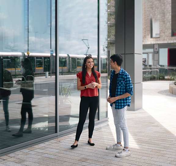 Two people standing outside a building with a glass door.