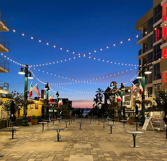 A city square is decorated with string lights and flags.