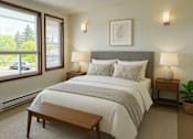 Thumbnail 1 of 8 - A bedroom with a large bed and a window overlooking a green area.