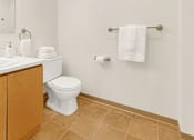 Thumbnail 5 of 8 - A white toilet sits next to a sink in a bathroom.