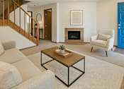 Thumbnail 4 of 8 - A living room with a fireplace, a chair, a couch, and a coffee table.