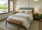 Thumbnail 6 of 8 - A bedroom with a large bed and a window overlooking a green area.