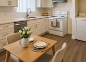 Thumbnail 2 of 8 - A kitchen with a table set for two with a vase of white flowers on it.