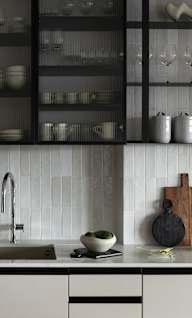 a kitchen with white tiles and black cabinets and a sink