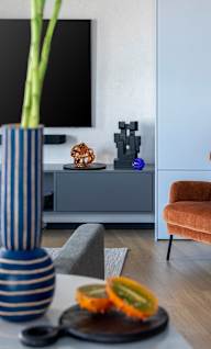 a living room with an orange chair and a blue and white vase