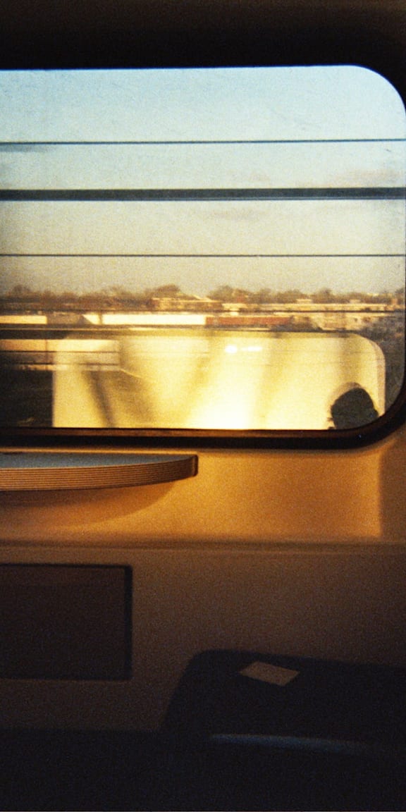 A train window with a view of a bridge and buildings.