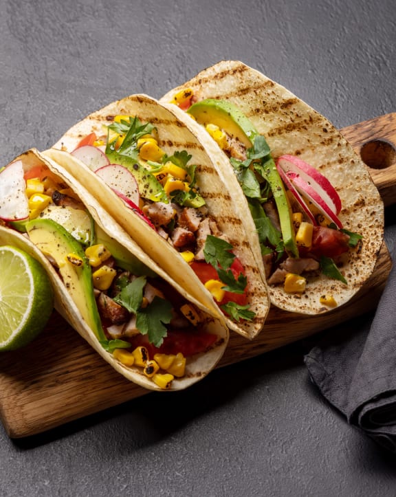 two tacos on a cutting board with a lime