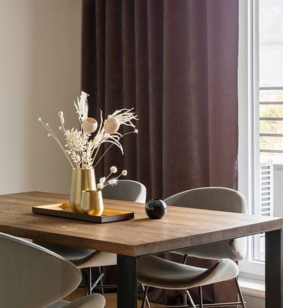 a dining table with chairs and a vase with flowers on it