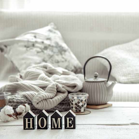 Living room with a couch, a teapot, a blanket, and decor featuring the word 'HOME'.