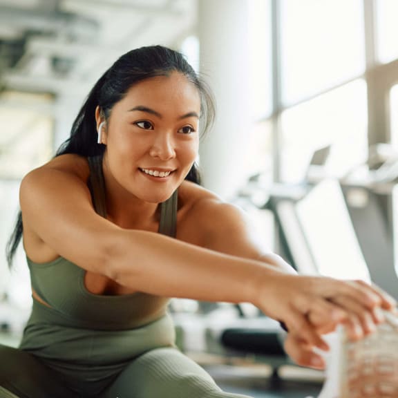 a woman sitting on the gym floor with her arms crossed