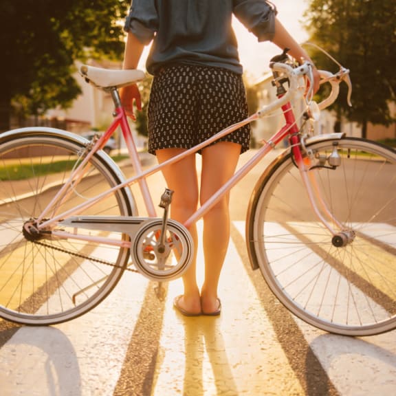 Woman Standing in Sun with Pink Bicycle