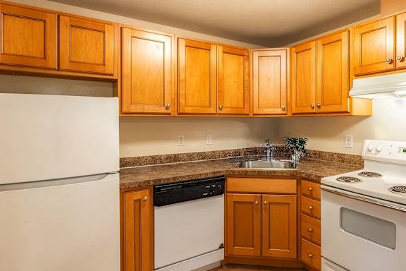 A kitchen with wooden cabinets and white appliances.