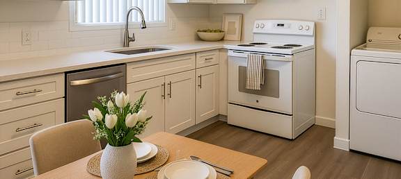 A modern kitchen with a wooden table set for two.