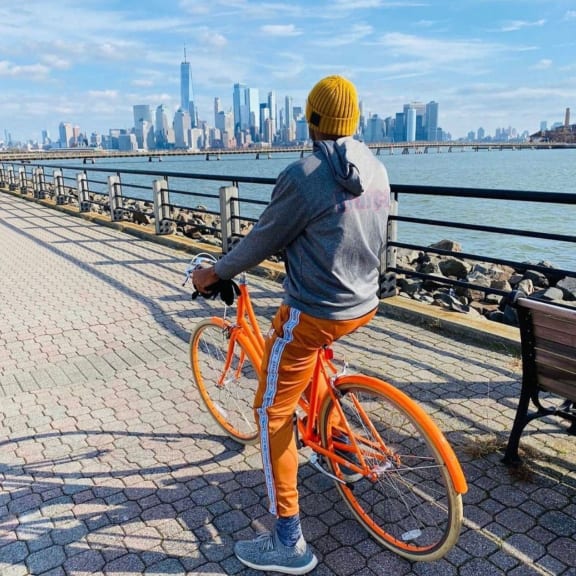 a man with an orange bike looking at the city skyline