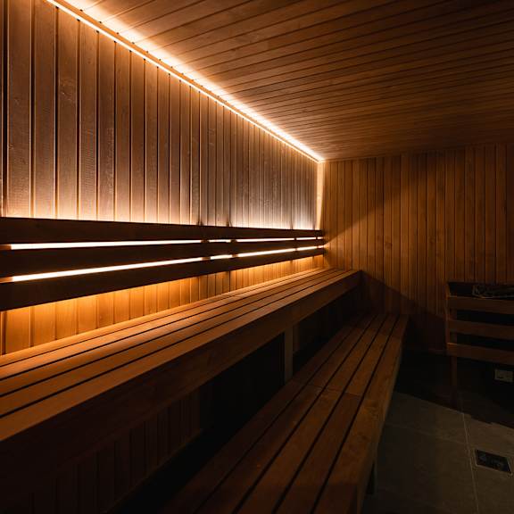 A row of wooden benches are lined up in a sauna.