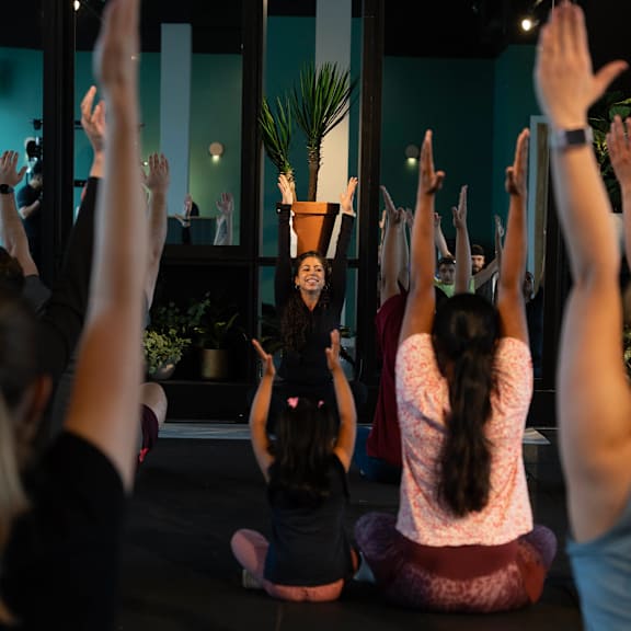 A group of people are sitting on the floor with their hands raised in a yoga class at Cherrywood Apartments, D18 VY3V, DUBLIN 18